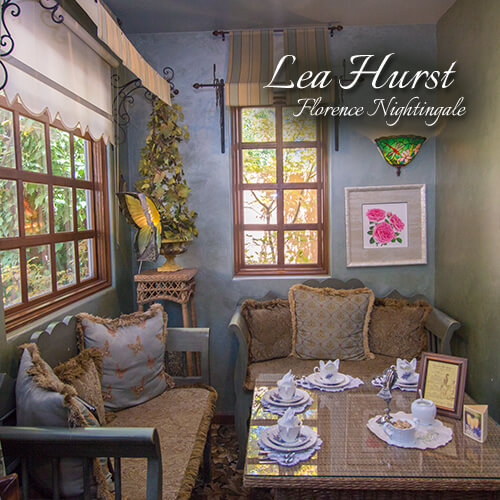 Lea-Hurst-Florence-Nightingale-Seating-Area-Teatime-Parlor-The-St-James-Tearoom Vintage seating alcove with windows, a lit wall sconce, and a framed picture of roses
