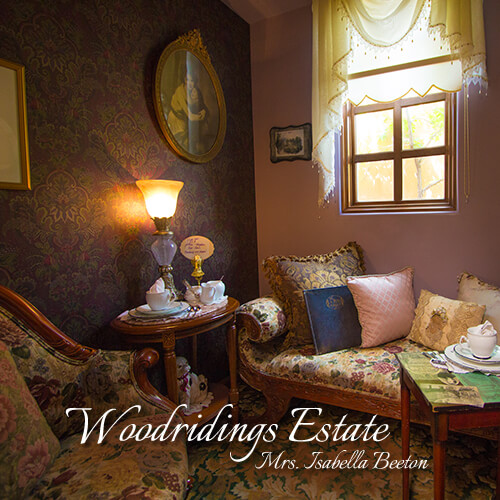 Woodridings-Estate-Mrs-Isabella-Beeton-Seating-Area-Teatime-Parlor-The-St-James-Tearoom Intimate tearoom booth with decorative porcelain cups, cushions, and elegant lace curtains