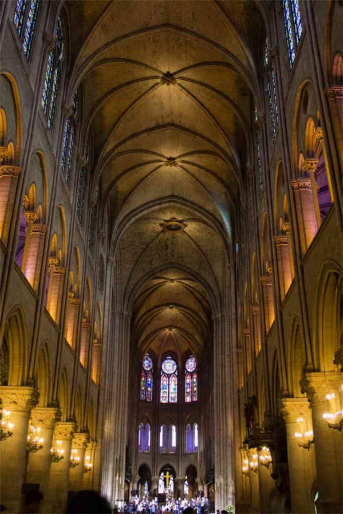 The interior of a large Gothic cathedral with vaulted ceilings, tall columns, stained glass windows, and warm lighting—viewed from the central aisle facing the altar—evokes a sense of reverence and timeless elegance, much like the experience of caring for fine china with thoughtful attention to every delicate detail.