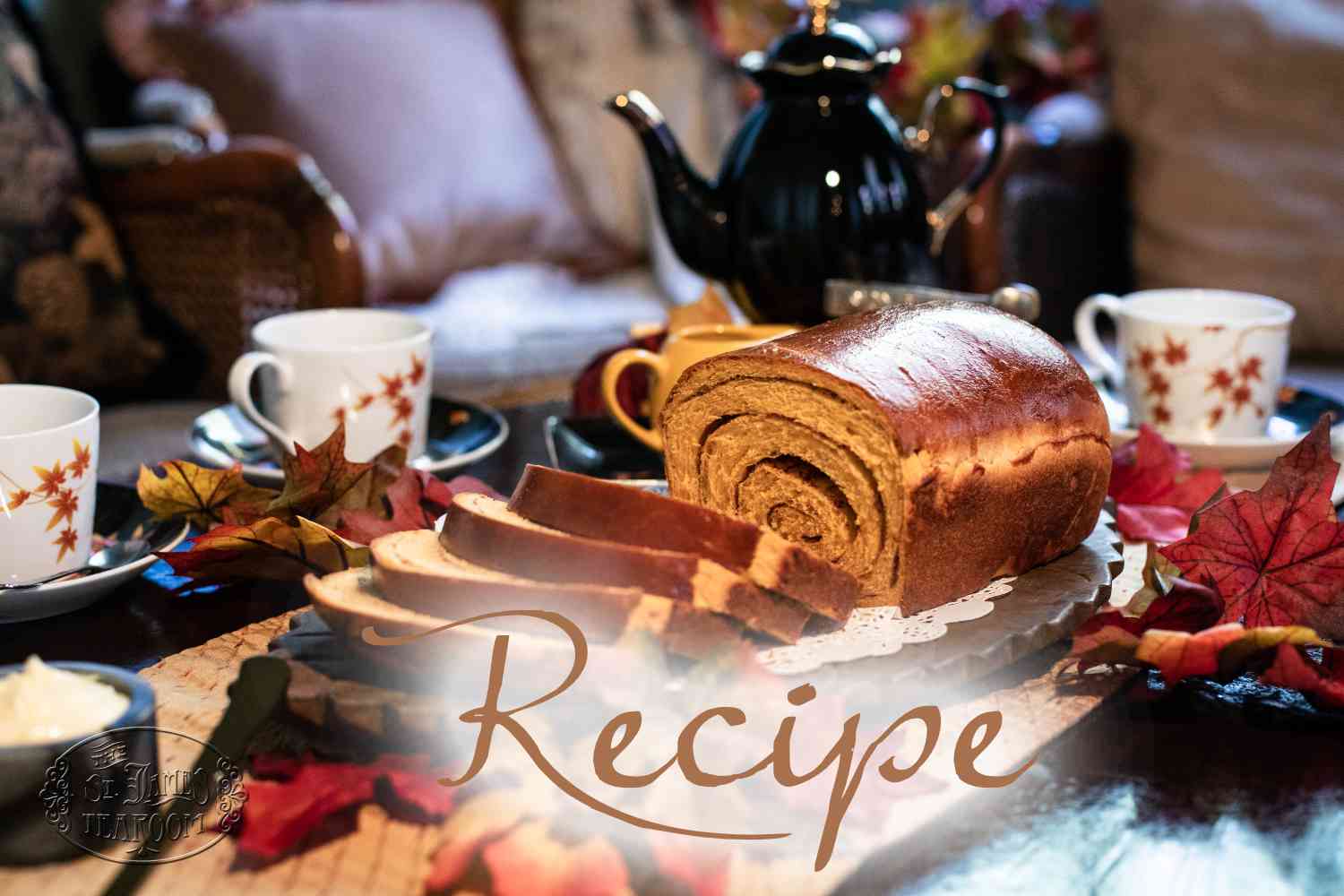 A sliced cinnamon swirl loaf rests on a table adorned with autumn leaves, teacups, and a teapot, with the word “Recipe” elegantly written across the image.