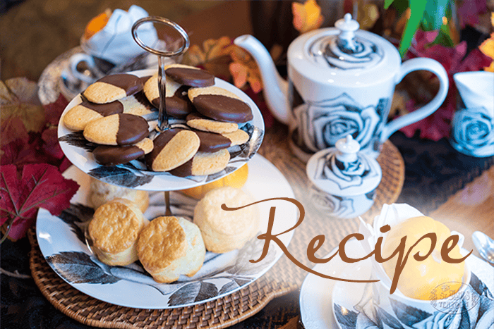 A two-tiered tray with French Butter Cookies and scones, surrounded by tea cups, a teapot, and autumn leaves. The word “Recipe” is written across the image.