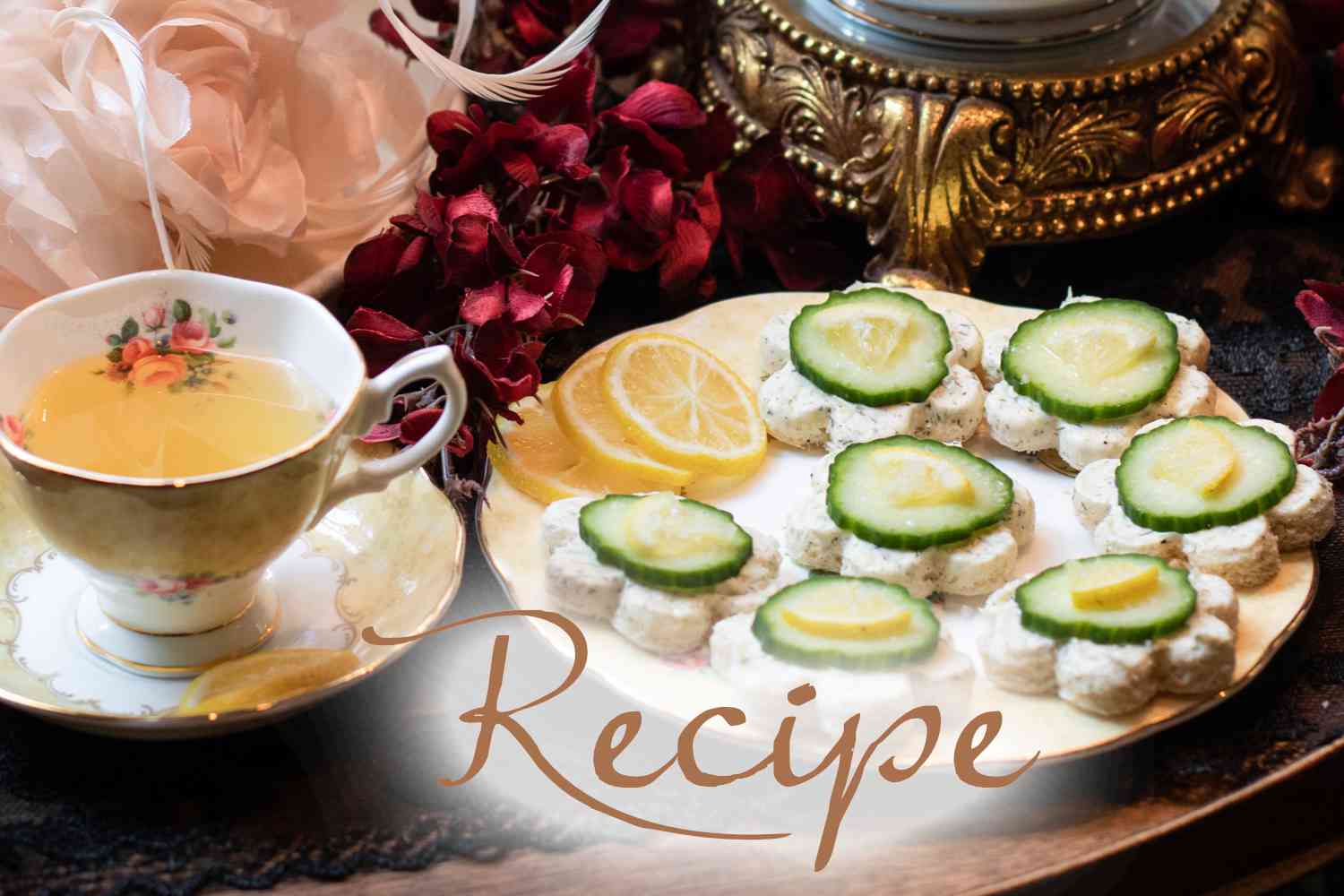A teacup with tea sits beside a plate of elegant Lemon Dill Cucumber Tea Sandwiches and lemon slices, surrounded by decorative flowers and ornate, golden decor. The word “Recipe” is overlaid at the bottom.