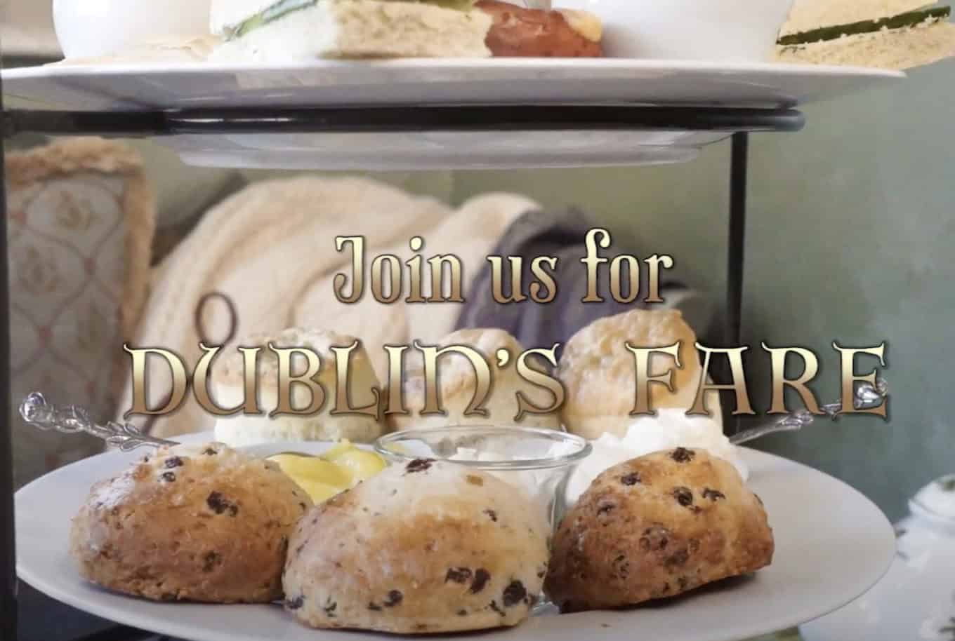 Afternoon tea setting with scones, cream, and lemon on a white plate. The text “Join us for DUBLIN’S FARE” appears over the image. In the background, there are sandwiches and blurred decor.