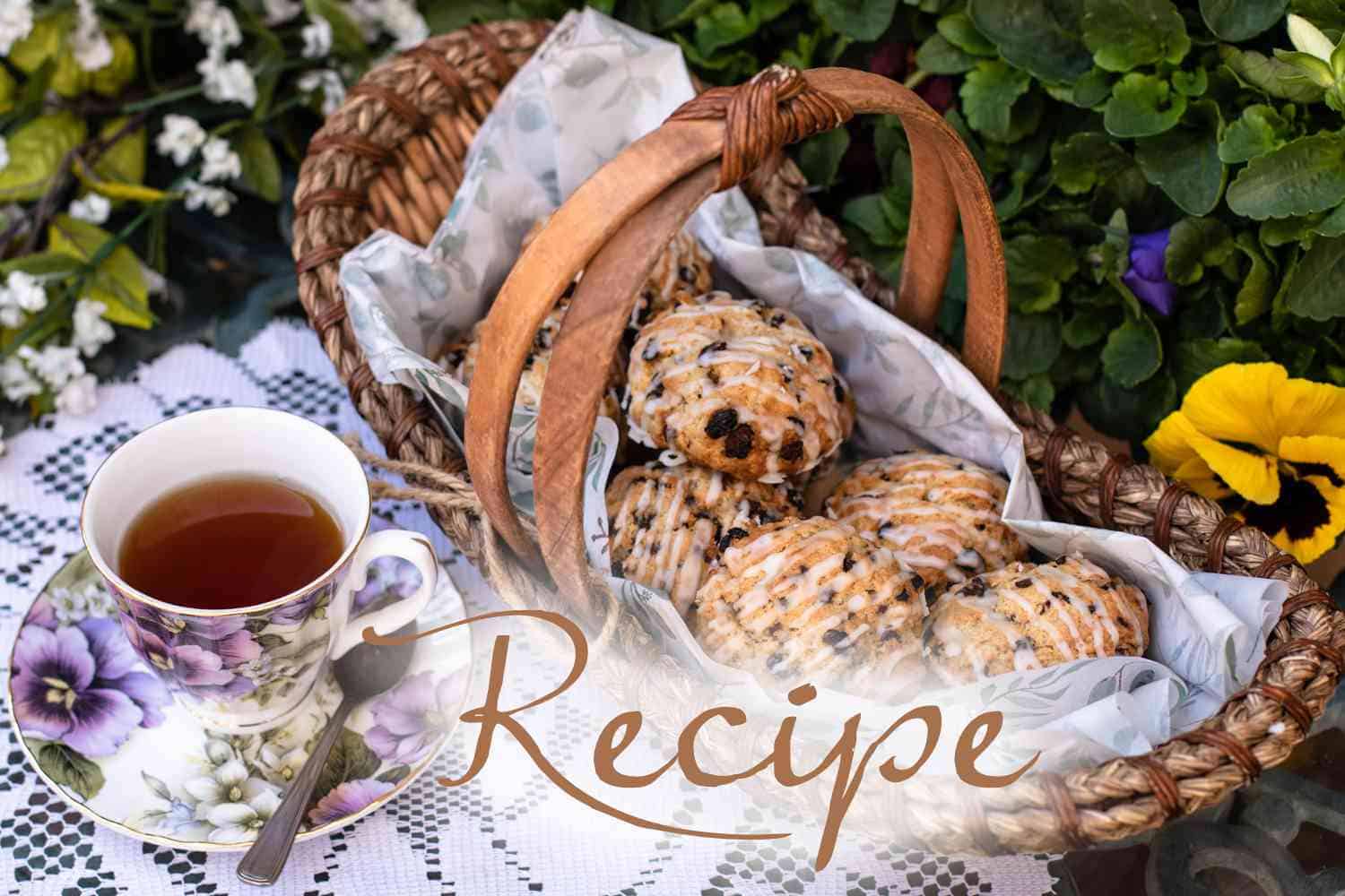 A basket of glazed scones with chocolate chips, set on floral paper next to a cup of tea in a flower-patterned teacup, surrounded by colorful flowers. “Easter Scones Recipe” is written across the image.
