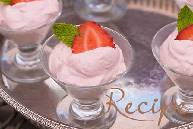 Pink strawberry mousse served in glass dessert cups, garnished with a strawberry slice and mint leaf, displayed on a silver tray. The word “Recipe” appears in the lower right corner.